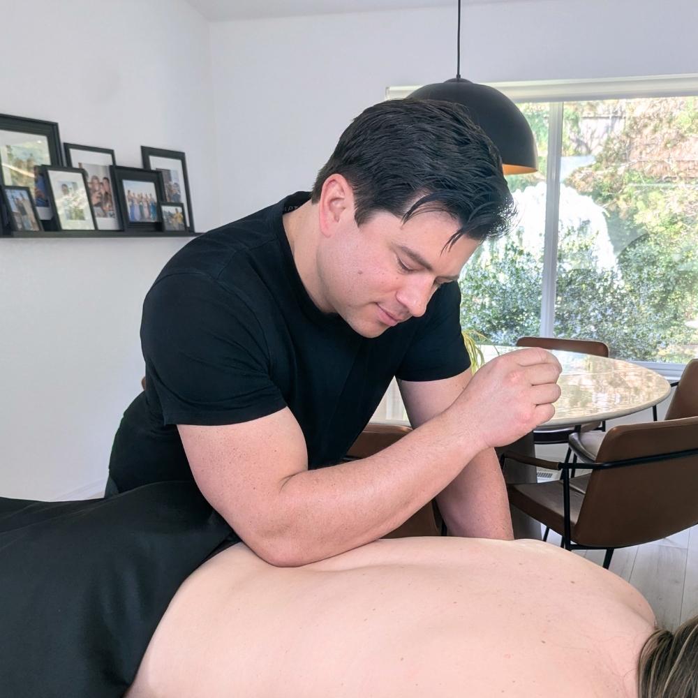 Mobile clinical massage therapist performing targeted back pain relief for a client in Bellevue, WA.